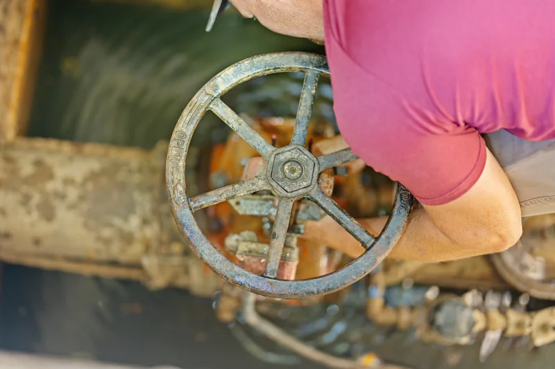 A team member working beside a large valve wheel in a commercial utility vault
