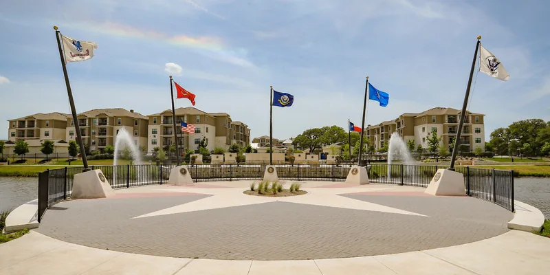 A flag plaza beside a pond and fountains in Leander, Texas.